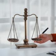 lawyer pointing at balance scale with pen in offic 2025 09 08 12 59 41 utc scaled e1757343011333 1